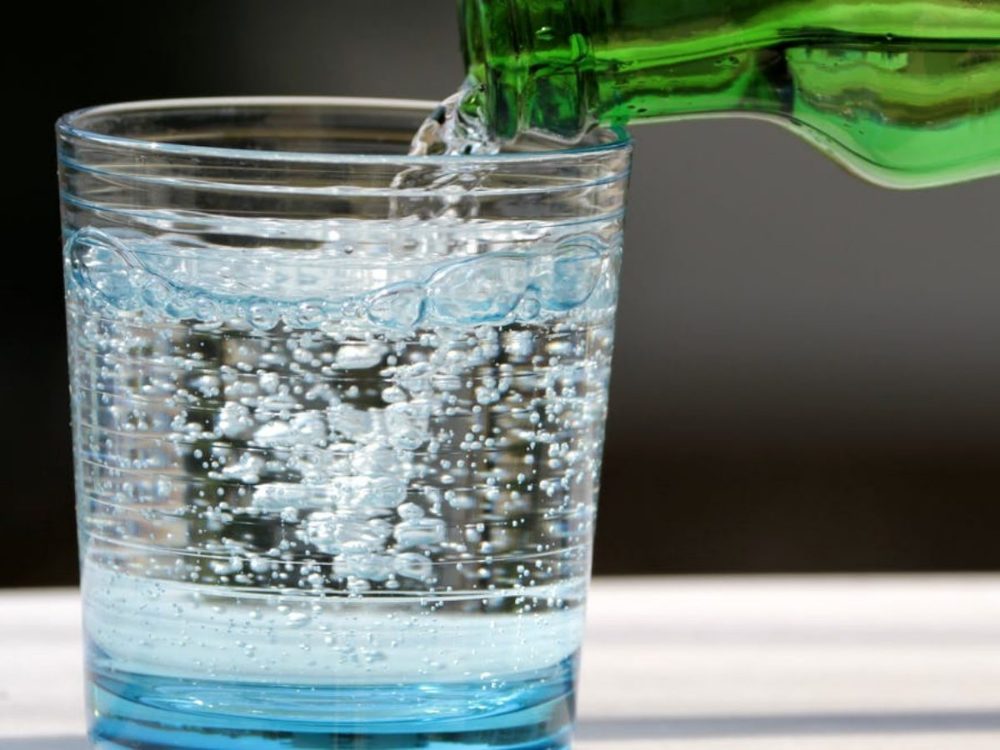 Eau pétillante versée d'une bouteille dans un verre
