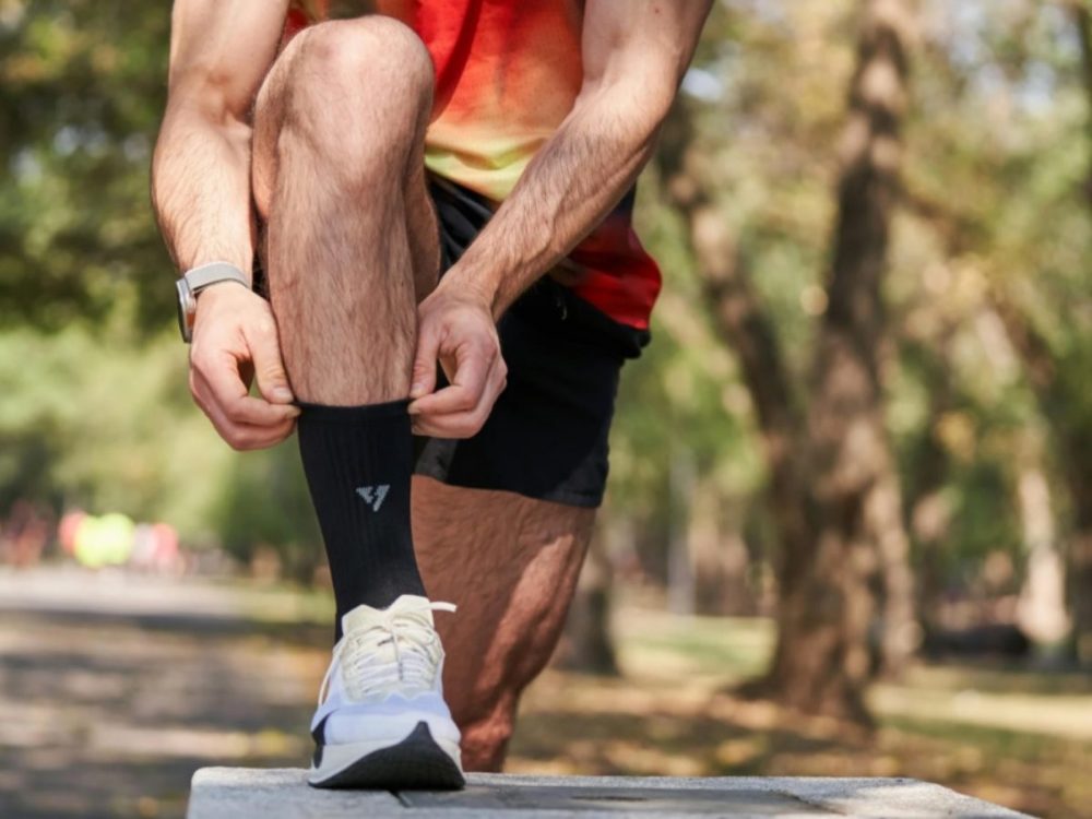 Coureur ajustant sa chaussette au bord du chemin